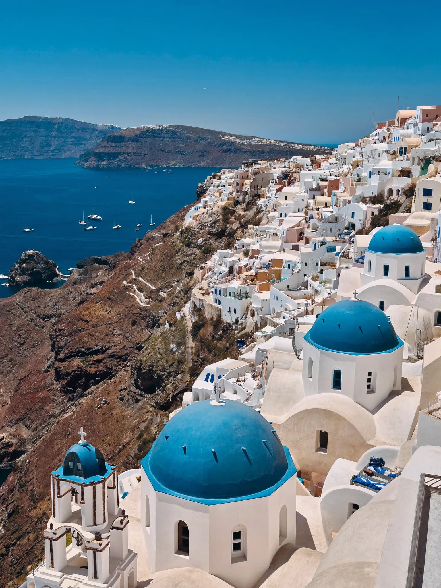 Village aux dômes bleus surplombant la mer Égée à Santorin